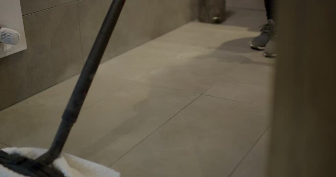 Close up of red extension rod nozzle spraying hot steam on inner rim of white ceramic toilet