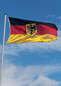 Wehende Deutschlandfahne am Flaggenmast mit Bundeswappen (Bundesadler) in der Mitte, Hochformat