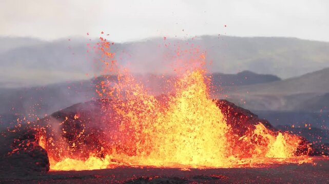 View of molten lava erupting from a volcanic fissure with glowing magma and smoke in Reykjanesbaer, Iceland.