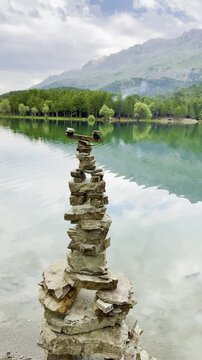 Mystical Vibe of Balanced Zen Stones Against a Forest Lake
