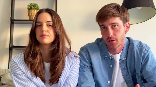 A young couple shares a candid conversation at home, expressing various emotions from serious discussion to shared smiles and laughter. They appear comfortable and connected, enjoying a casual moment 