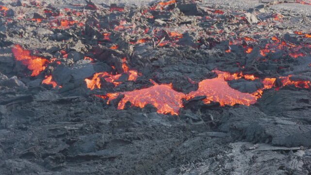 View of molten lava flowing over dark volcanic rock in Reykjanesbaer, Iceland.