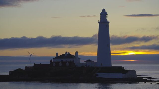 Scenic shot of St Mary's Lighthouse on its rocky island at Whitley Bay during a vibrant summer sunrise over the North Sea.