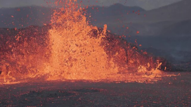 View of lava fountain erupting from the ground with glowing molten rock and volcanic debris in Reykjanesbaer, Iceland.