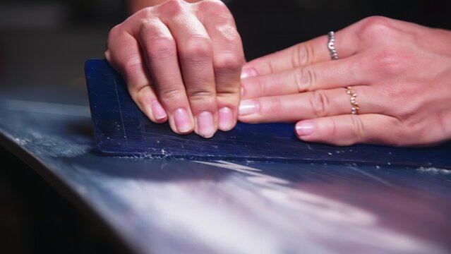 Person sanding a dark blue surface with a hand-held sander