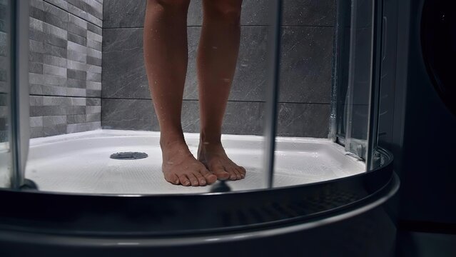 Person standing barefoot in shower with tiled wall background