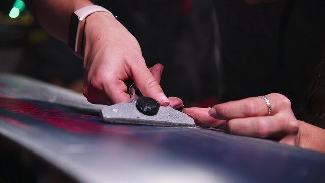 Person using a hand planer tool on wood surface in workshop