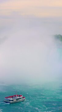 Soft haze cloaks waterfall behind boat quietly. Gentle vapor masks moving watercraft from view when veiled by mist. Calm foggy mist gently obscures waterfall and watercraft behind boat quietly