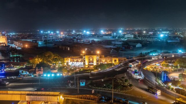 View of the illuminated KPT Ground Keamari building surrounded by busy roads and city lights at night in Karachi, Sindh, Pakistan.