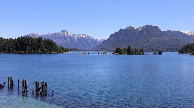 View of Isla Victoria on Nahuel Huapi Lake with snow-capped mountains and clear blue sky in San Carlos de Bariloche, Rio Negro Province, Argentina.
