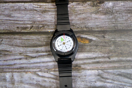 a wrist-mounted compass designed for outdoor activities like hiking and camping, features a black rubber watch strap and a liquid-filled dial for accurate navigation