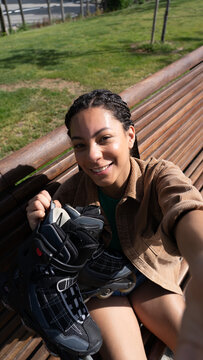 Young woman smiling holding inline skates outdoors