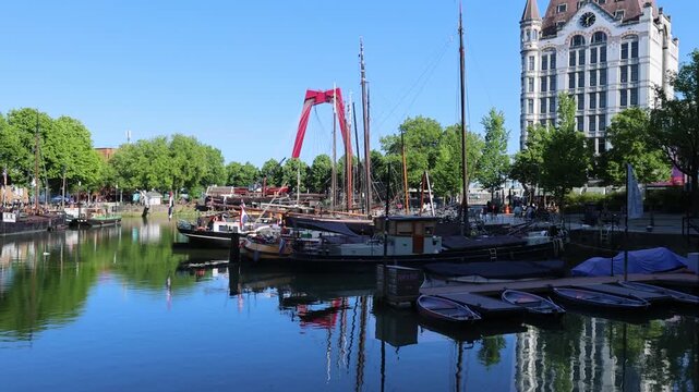 View of the historic Oude Haven with old boats, the Witte Huis building and the red Willemsbrug bridge under a clear blue sky in Rotterdam, Zuid-Holland, Netherlands.