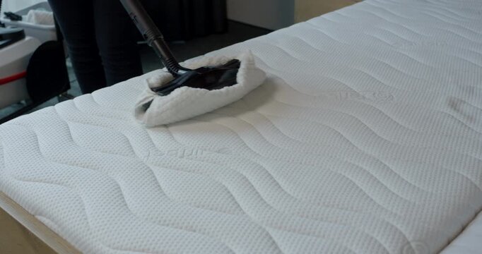 Overhead tracking shot of steam machine floor tool sanitizing a modern white ergonomic bedroom mattress