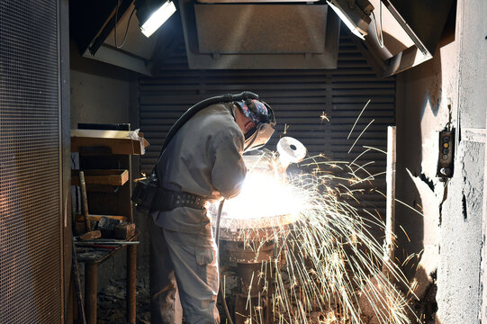Welder in protective clothing at the workplace in an industrial company in steel construction