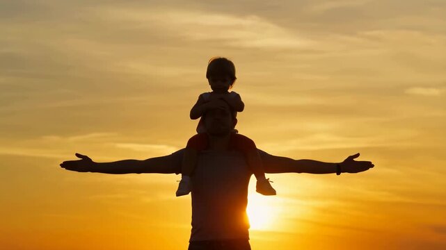 Silhouette of a father with child on shoulders against a sunset backdrop. Celebrating family bonds and joyful moments in nature