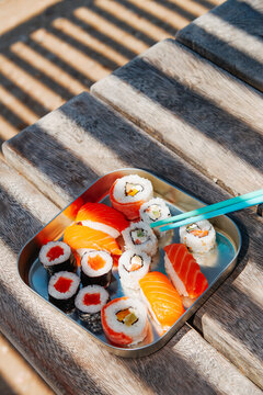 a sushi box rests on a wooden bench