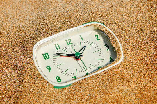 a close-up of a green clock in the sand