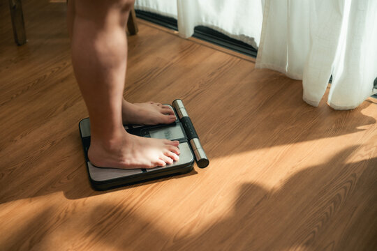 Plus Size Woman Stepping on Weighing Scale During Weight Management Journey
