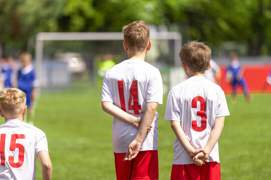 Youth Soccer Players Waiting on Sideline: Kids in White and Red Uniforms Watching Game