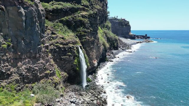 Aerial view of Cascata do Mito waterfall crashing into ocean Madeira