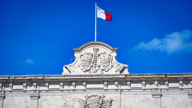 Maltese National Flag Waving over Historic Government Building Facade