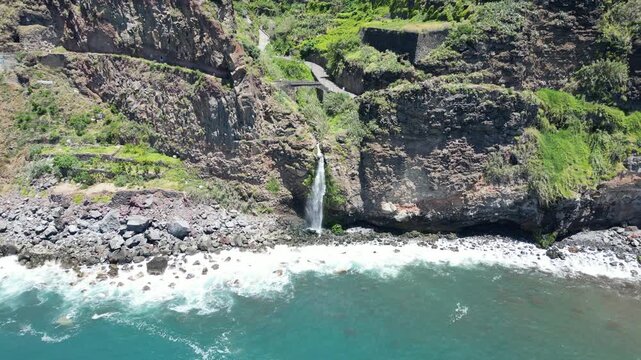 Aerial view of Cascata do Mito waterfall crashing into ocean Madeira