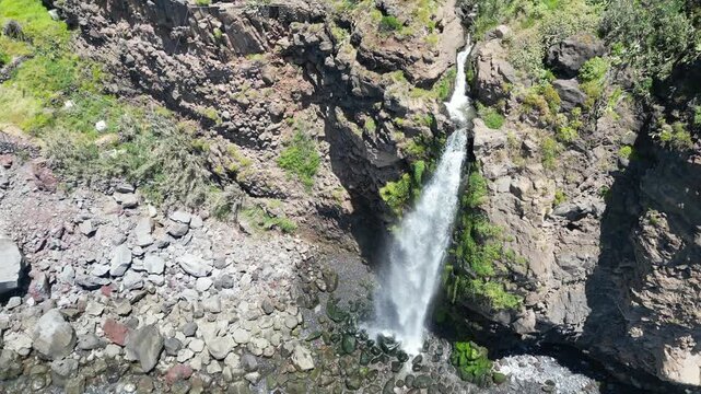 Aerial view of Cascata do Mito waterfall crashing into ocean Madeira