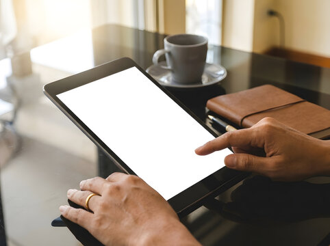 Close up of hand using digital tablet with blank white screen | Businessman operating touchpad tablet device at black office desk | Mockup screen on tablet computer with coffee cup and notebook 