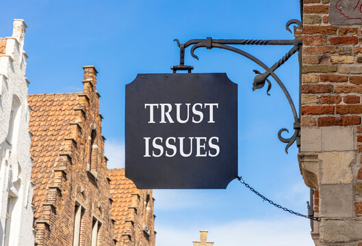 Trust issues symbol. Concept word Trust issues on beautiful black sign on street in Brugge. Beautiful blue sky and buildings background. Business trust issues concept. Copy space.