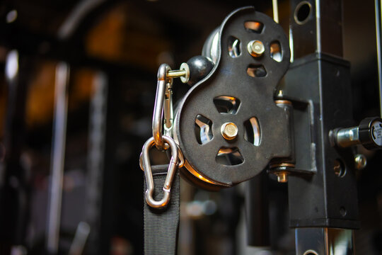 Close-up of home gym pulley system with steel cable and carabiner, industrial fitness equipment detail with copy space.