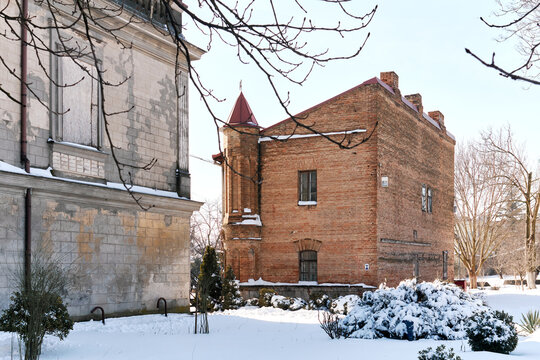 Red brick historic building with turret beside classical facade in winter snow