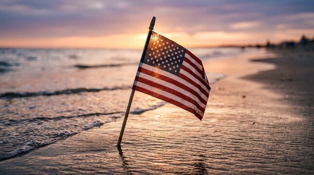 patriotic beach remembrance, a small american flag stands in wet sand as gentle waves lap nearby at sunset