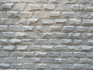 Obraz premium Close-up of modern white textured stone wall cladding, natural white stacked stone exterior facade.