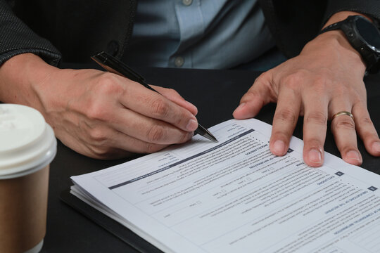 Serious business hand holding pen to sign legal document paper for non disclosure agreement with focused professional expression