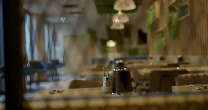 Slow pan shot focusing on empty tables in a modern restaurant interior during daytime operations