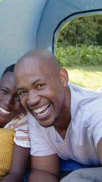 Vertical video: Reaching dad and smiling youth leaning into phone in tent taking selfie with pillow