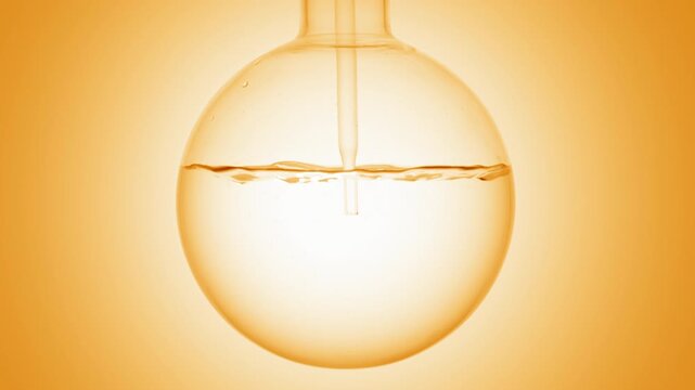 Close-up of perfectly clear liquid injected through a long dropper into a round-bottom flask, causing swirls and bubbles on orange ramp background