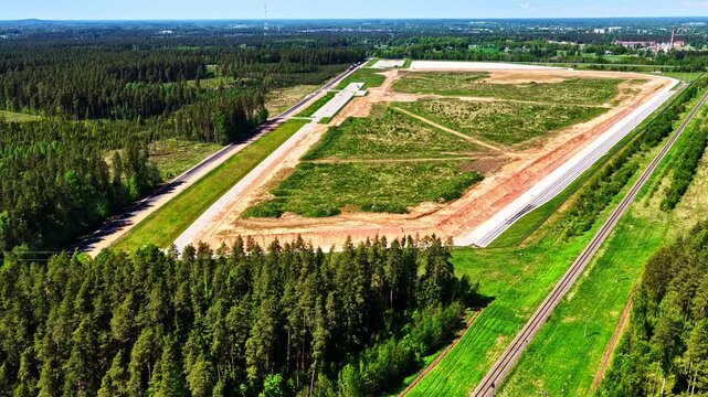 Large land development project near a forest and railway, industrial park plot in aerial view