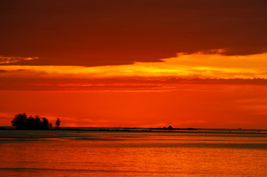 Vibrant Borneo sunset over calm waters featuring intense orange and red hues across the evening sky.