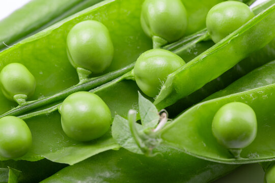 Green peas inside open pods in a macro view