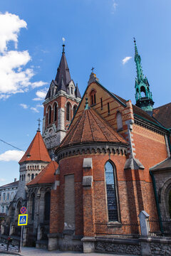 Historic St. Stanislaus Church in Chortkiv, Ternopil region, featuring Gothic Revival architecture, brick walls, towers, and spires under a blue sky.