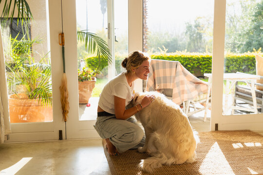 young woman playing with her English cream golden retriever dog at home