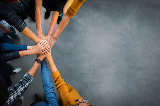 Diverse group of hands joining together in a circle for unity and teamwork during a meeting