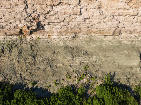 Geological layers of limestone and blue clay on a coastal cliff glint structure close up, soil stratification texture background.