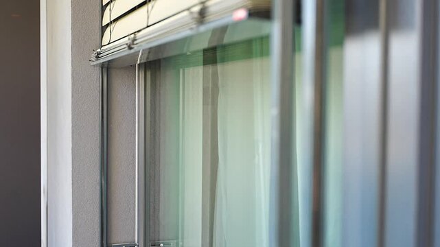 Exterior window blinds automatically closing over a large apartment window. Smart home automation and energy efficient sun protection concept.