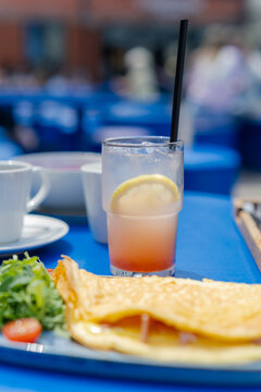 Close-up of a refreshing grapefruit lemonade with ice and a lemon slice on a blue table at a summer terrace