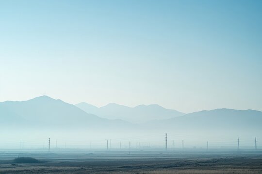 Smoggy horizon with barely visible mountain range and haze over rural plain, atmospheric sky and distant power line