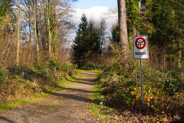 Naklejka premium Forest road with traffic sign no motor vehicles allowed at Swiss village of Rümlang on an autumn day. Photo taken November 27th, 2025, Zurich Rümlang, Switzerland.