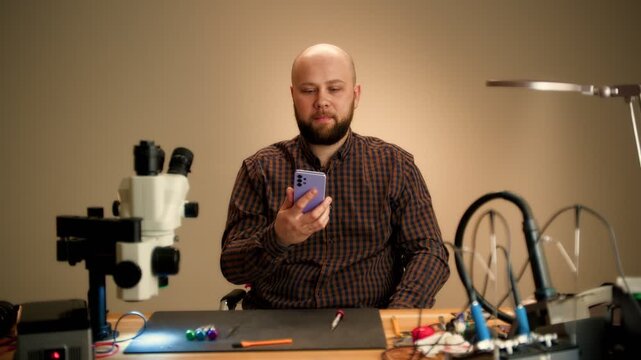 Repair Technician Inspecting Smartphone at Electronics Workbench